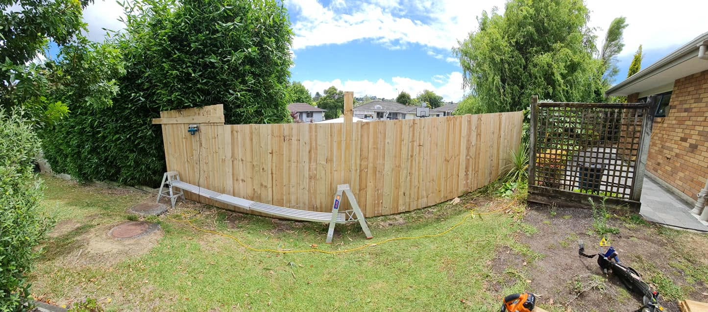 Wide view of a newly built paling fence and gate around a lawn