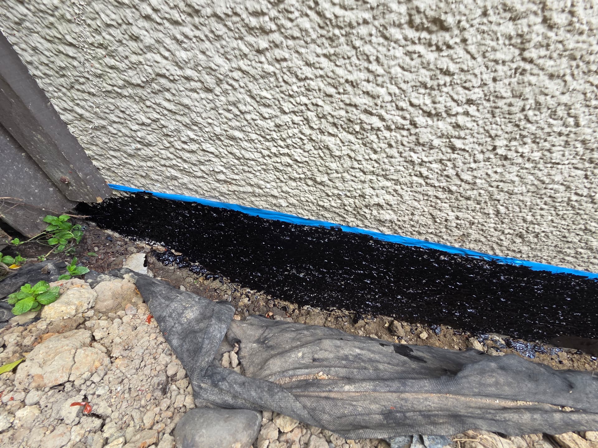 Close up of a black bitumen waterproof seal along a wall base