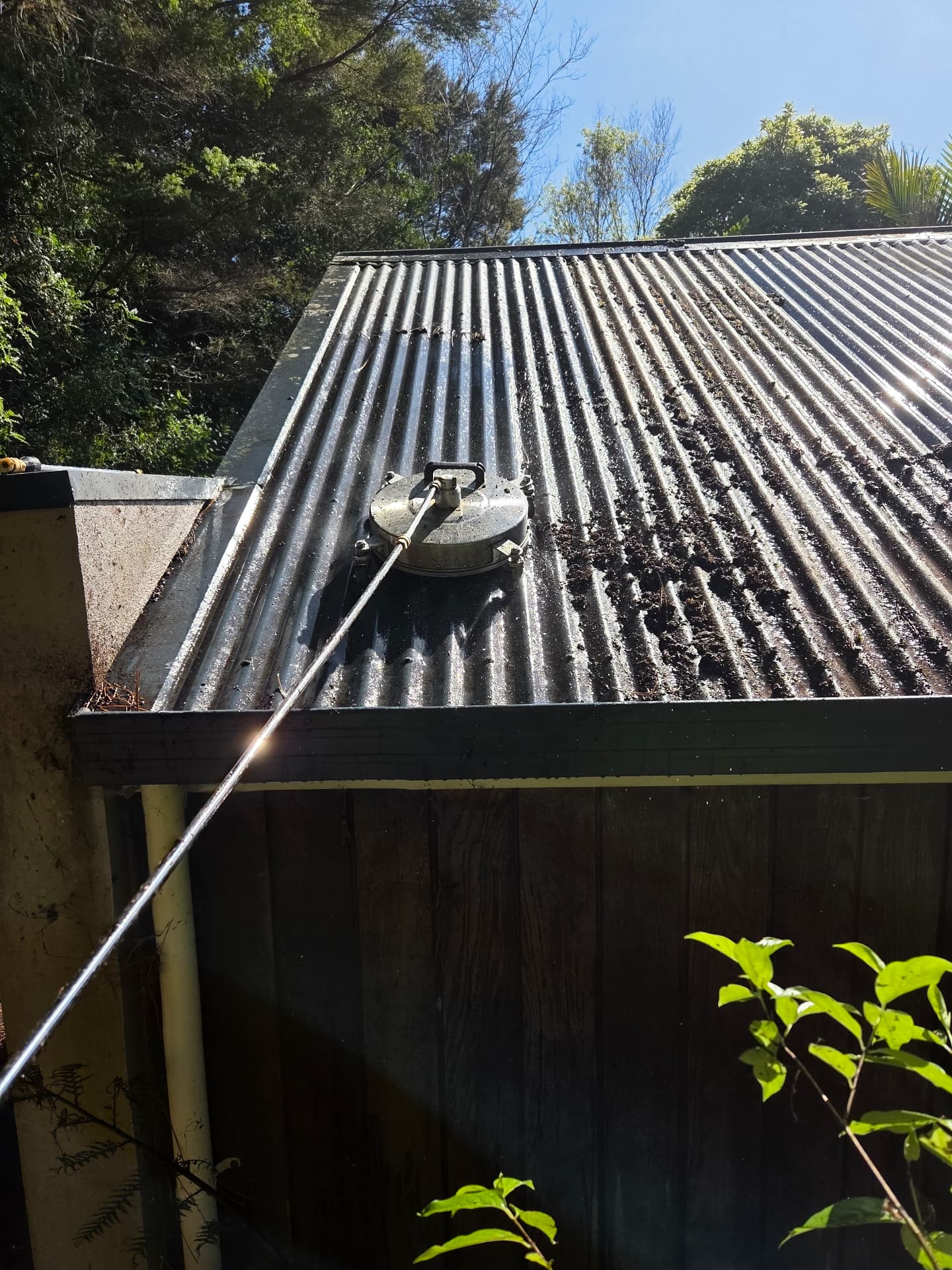 Moss and debris being blasted off a corrugated iron roof