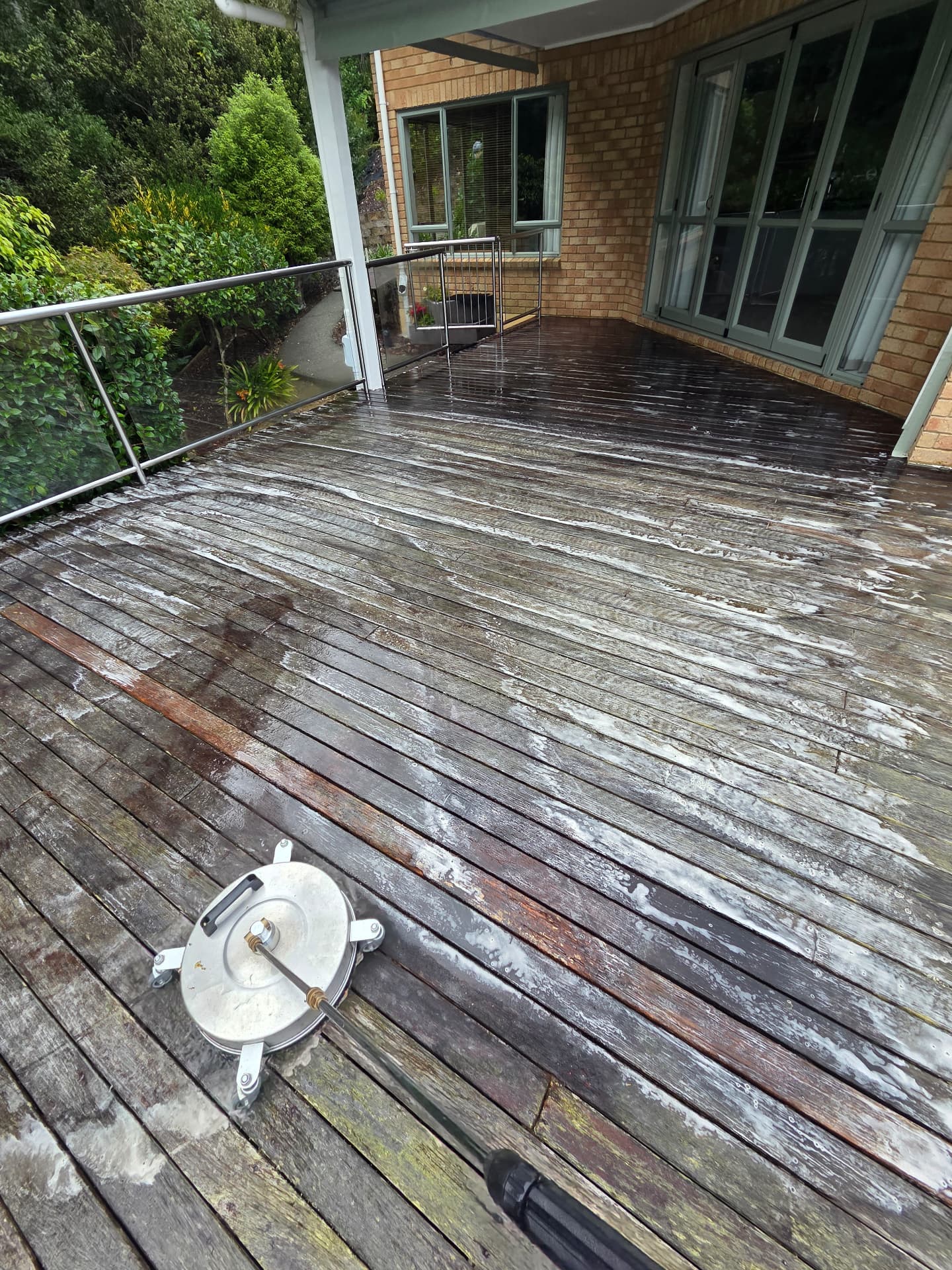 Weathered timber deck being cleaned with a rotary surface washer