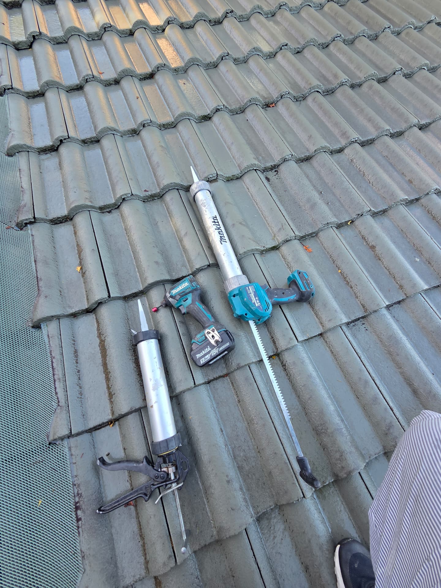 Makita tools laid out on a tile roof during a repair job